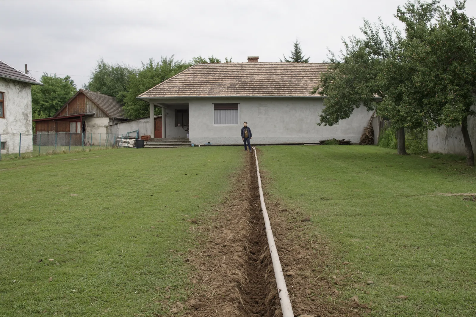 Hosszú udvar egy hetesi családi háznál, a kerítéstől a házig futó vezeték nyomvonalával